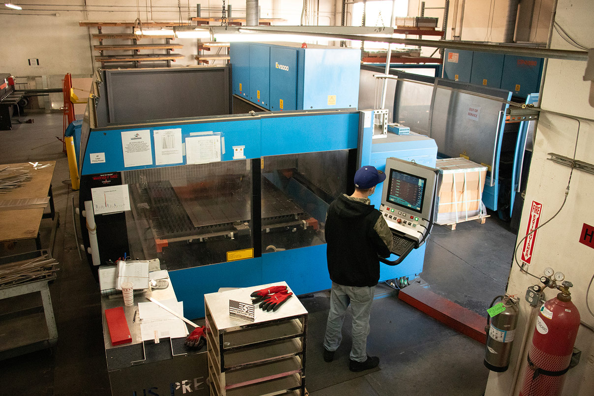 Operator running an Eagle 6000 fiber laser cutter, monitoring the cut on the control screen above the cutting bed.